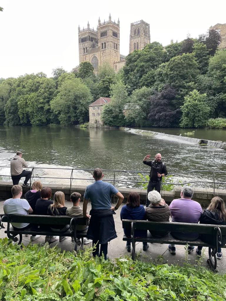 Peter, from Walkabout Durham, with a group of tourists across the River Wear from Durham Cathedral