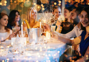Christmas party Friends celebrating Christmas or New Year eve. Party table with champagne.