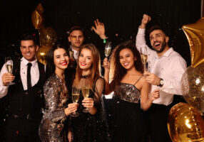 New Year's Eve party night Happy friends with glasses of sparkling wine celebrating New Year on black background